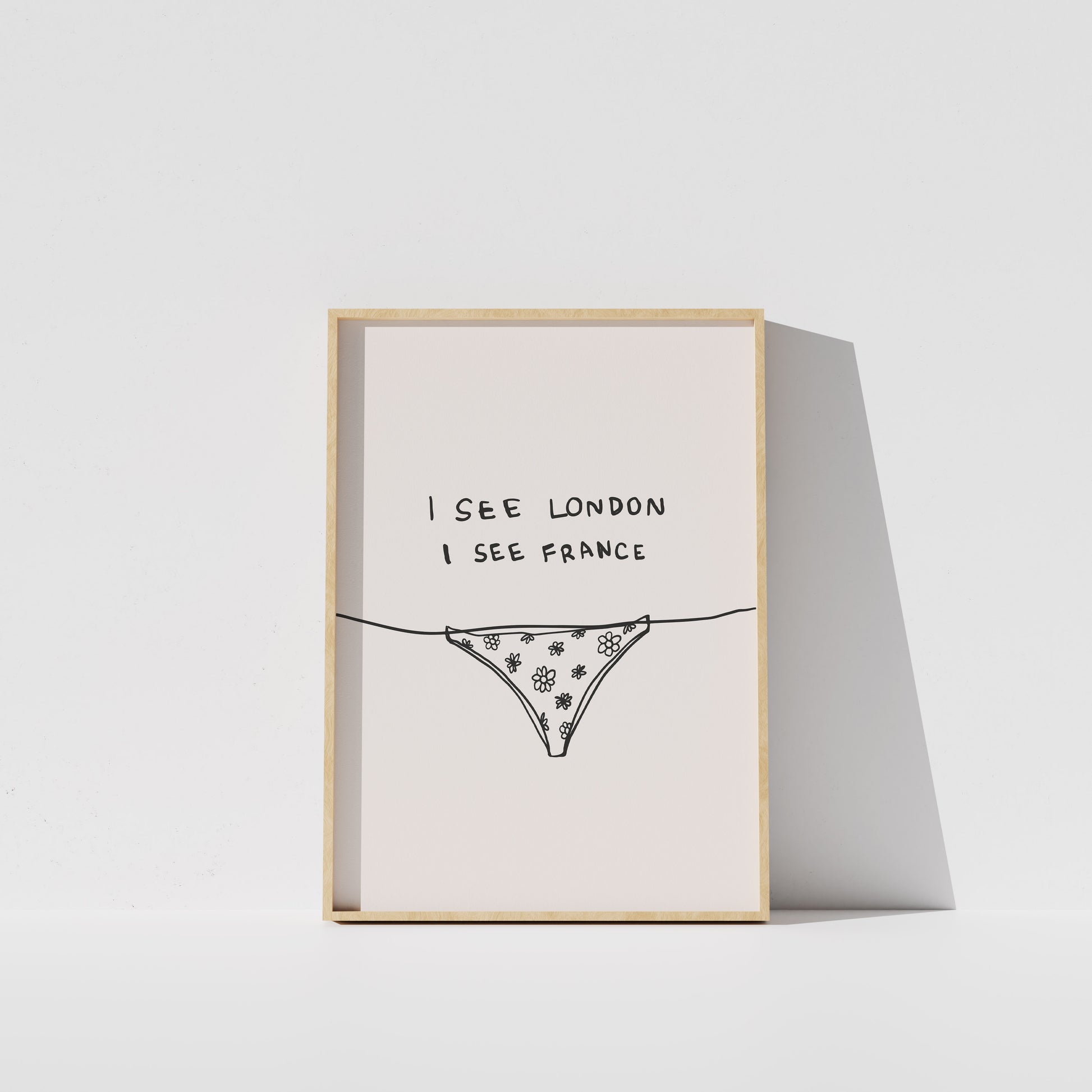 A framed print with the text "I see London I see France" and an illustration of a bikini bottom.