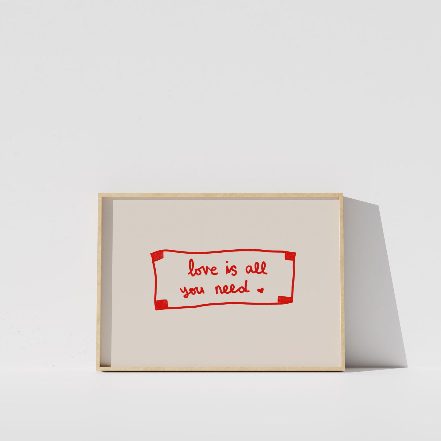 A simple white wall with a framed red and white sign that reads "love is all you need".