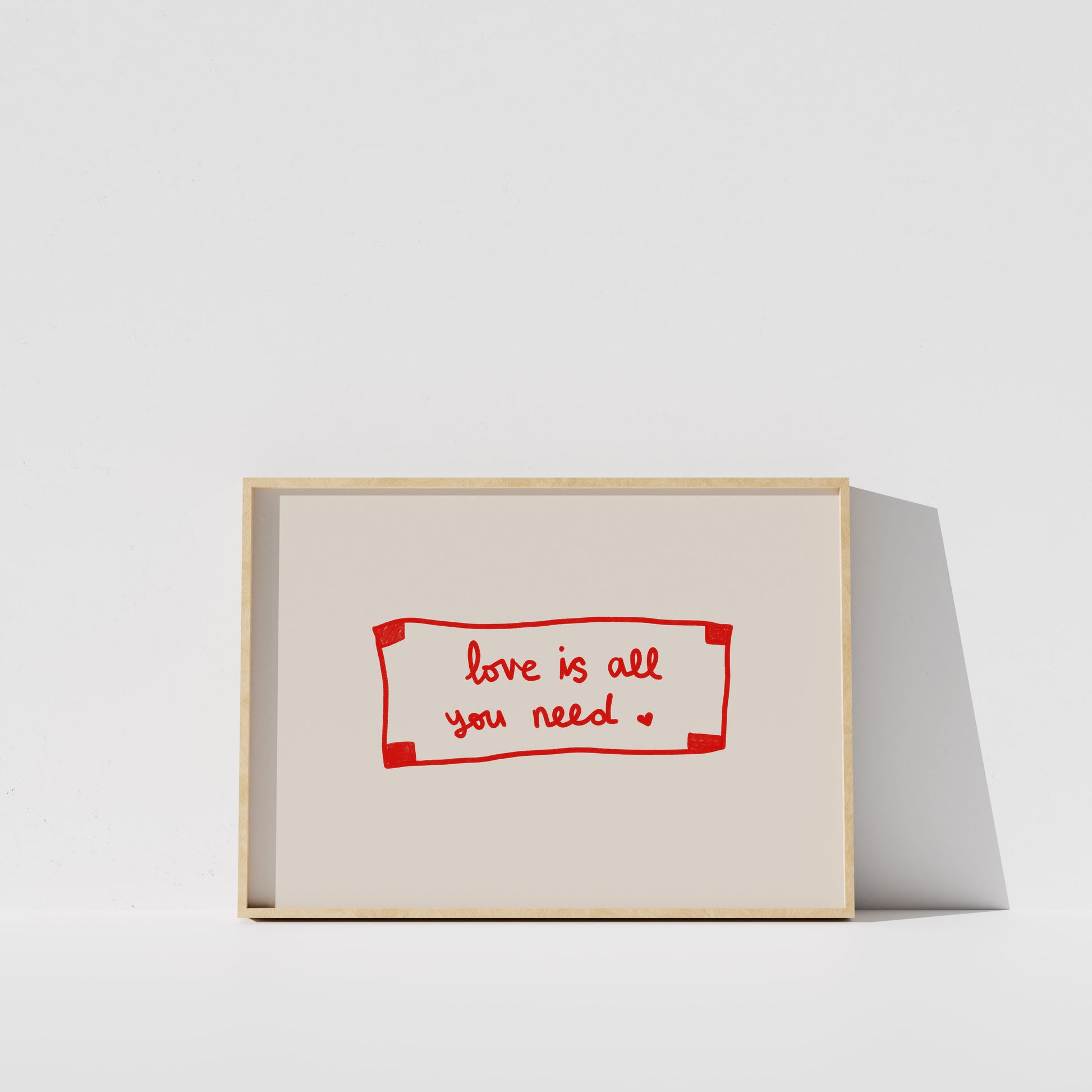 A simple white wall with a framed red and white sign that reads "love is all you need".