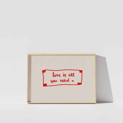 A simple white wall with a framed red and white sign that reads "love is all you need".
