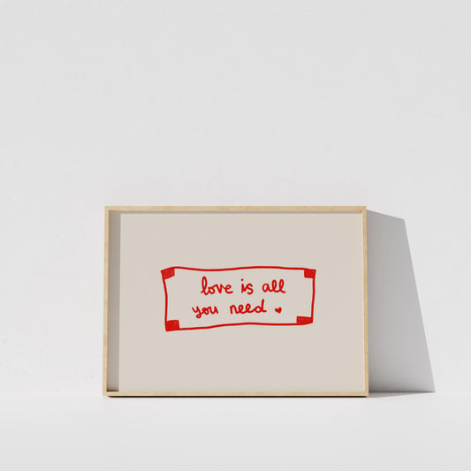 A simple white wall with a framed red and white sign that reads "love is all you need".