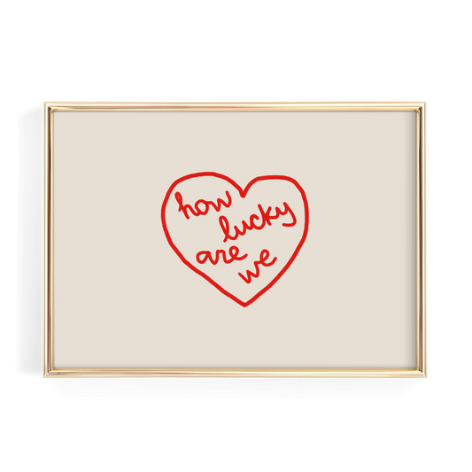 A framed image with a red heart-shaped design containing the text "how lucky are we" written in cursive.