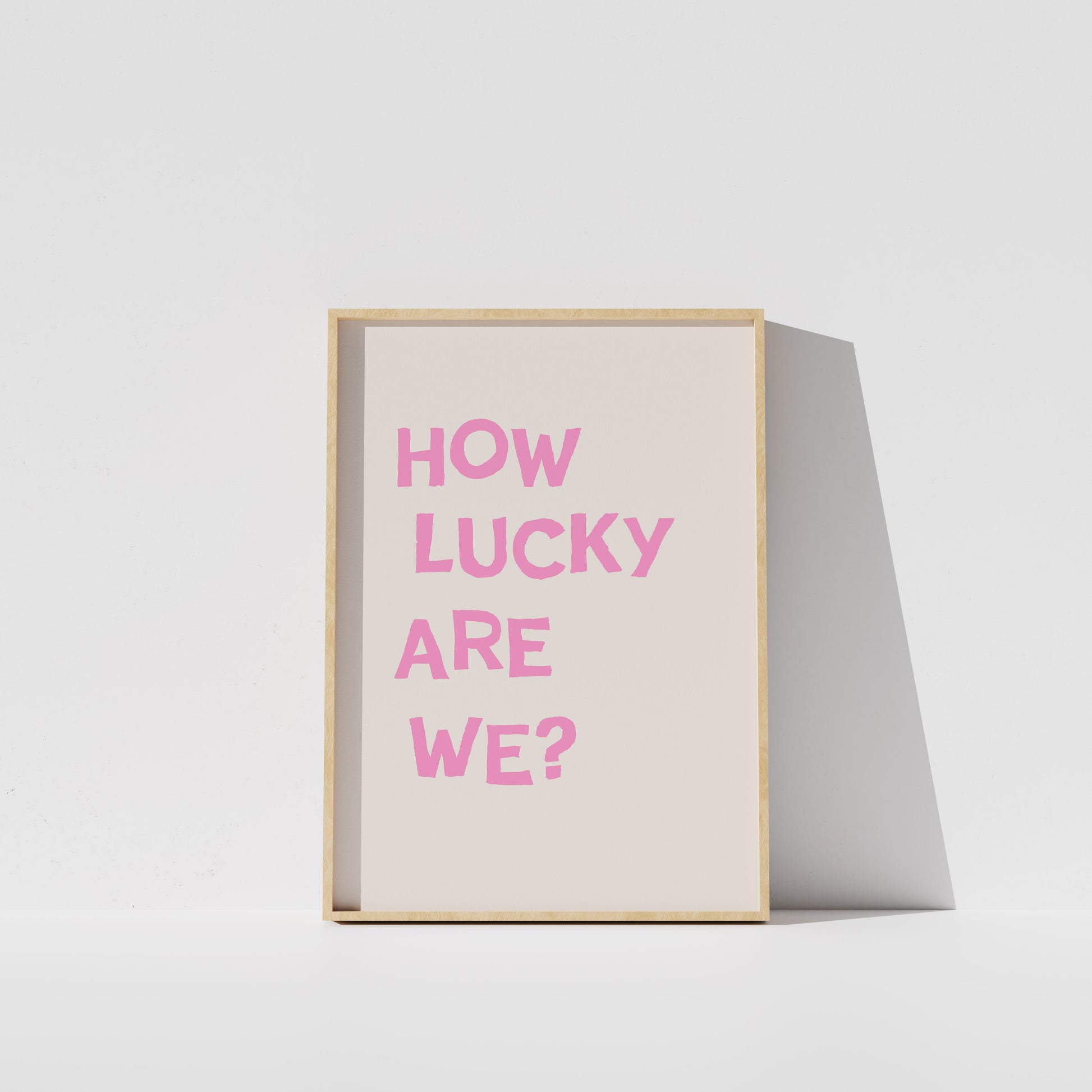 A framed poster with the text "HOW LUCKY ARE WE?" in pink letters against a white background.