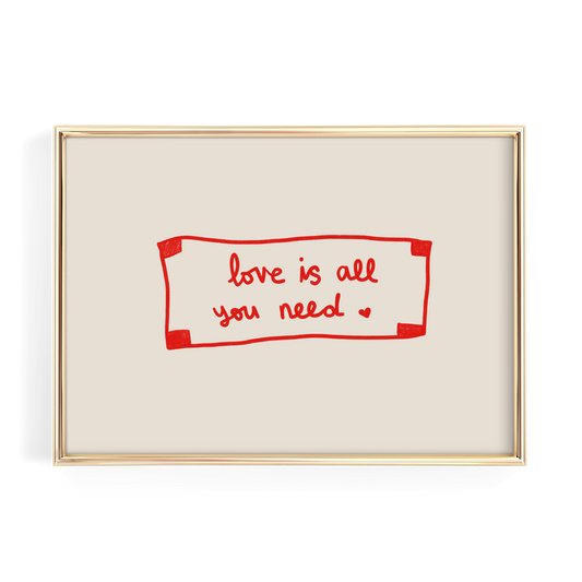 a framed piece of art with the text "love is all you need" written in red cursive on a beige background.