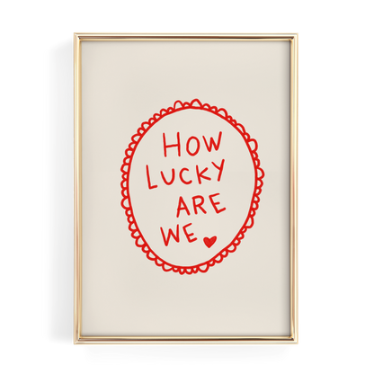a framed piece of art with the text "HOW LUCKY ARE WE" written in a red circular design.