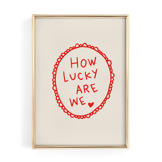 a framed piece of art with the text "HOW LUCKY ARE WE" written in a red circular design.